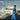 Baseball player in blue uniform swinging bat at batting cage under cloudy sky