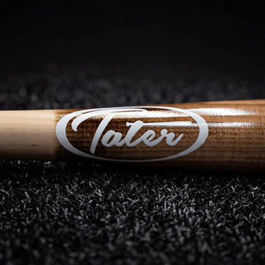 Tater wood baseball bat with branded logo on dark turf background