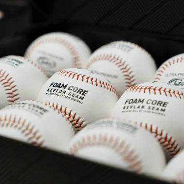 Close-up view of Tater Foam Core Kevlar Seam baseballs stacked in bulk, showcasing premium leather cover and red stitching