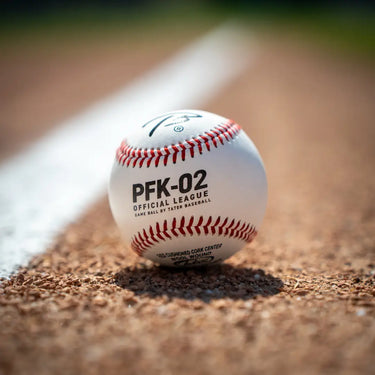 Tater PFK-02 Official League high school game baseball with red stitching, resting on the infield chalk line