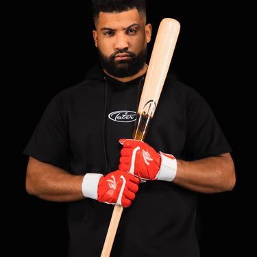 Player in a black Tater shirt and red batting gloves holding a Tater X12 Pro bat on his shoulder