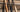 Three used Tater wood bats in natural, black and two-tone finishes leaning against a weathered wooden dugout bench